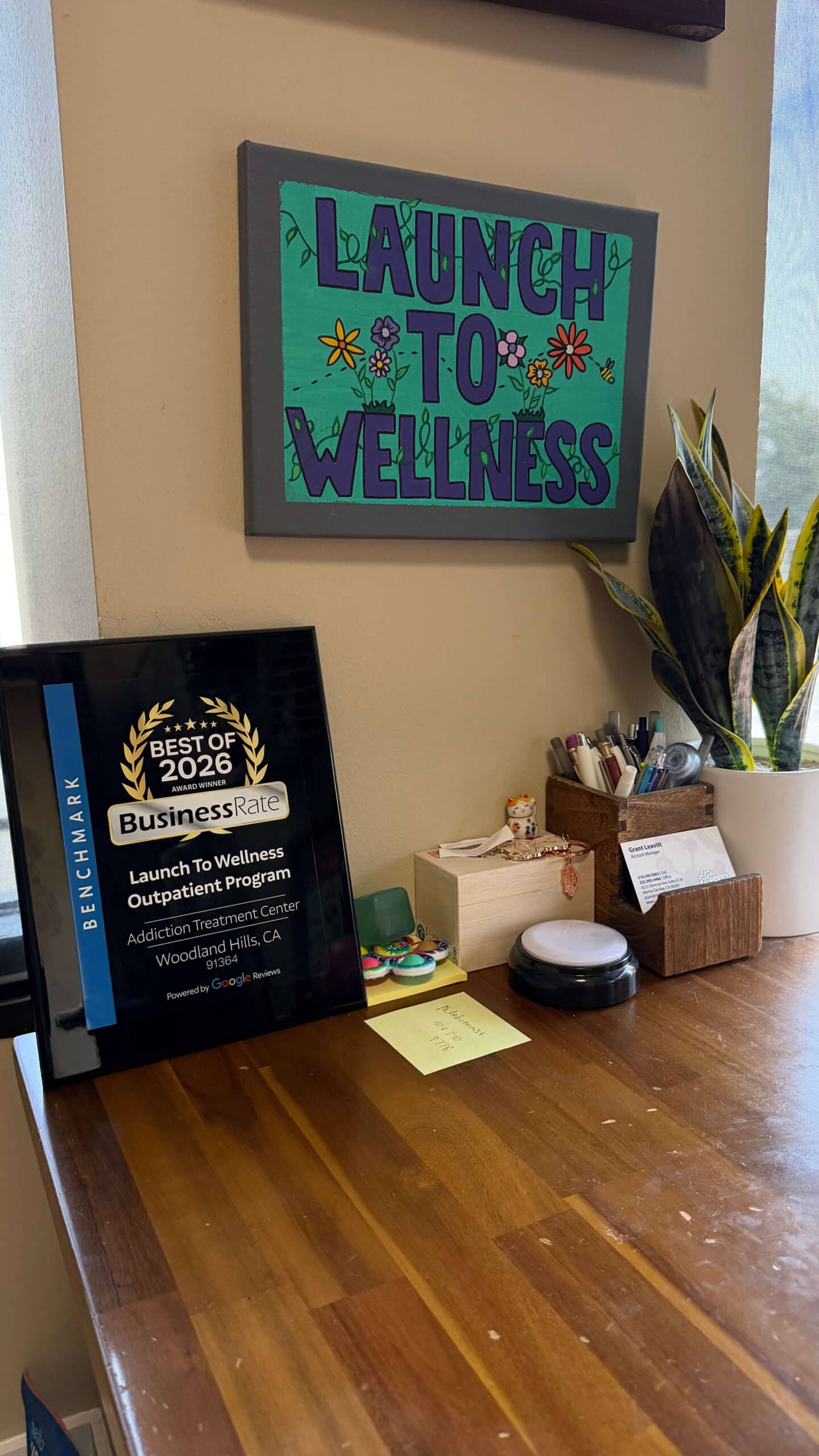 Reception desk with a handmade Launch To Wellness painting and a Best of 2026 award